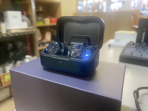 The Noble Osprey True Wireless Stereo Earphones inside of aluminum charging case, powered on
